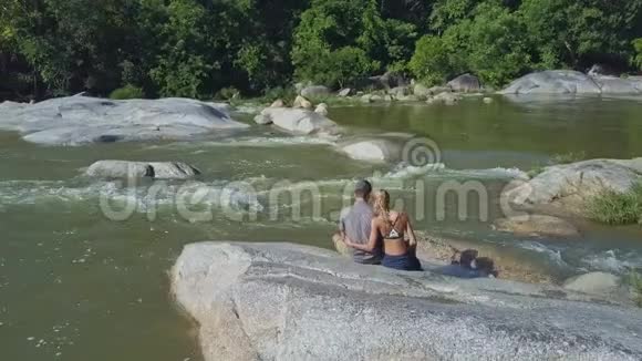 无人看夫妇坐在溪边与丛林视频的预览图