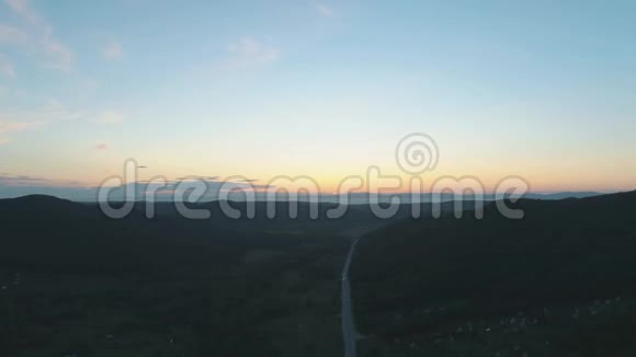 空中无人机在日落时看到青山之间的道路视频的预览图