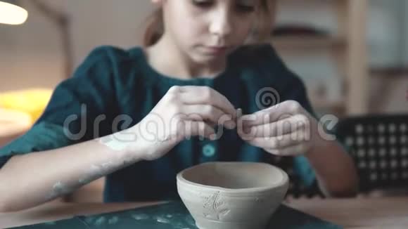 孩子正在做一盘粘土陶艺课小女孩在粘土邮票上做图案视频的预览图