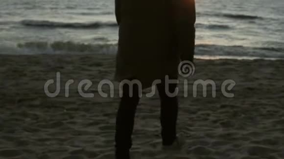 孤独的人走在海边享受日落年轻的男性欣赏海滩上的海浪视频的预览图