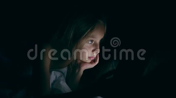 悲伤的年轻女孩晚上在床上使用平板电脑看着平板电脑屏幕疲惫而严肃视频的预览图