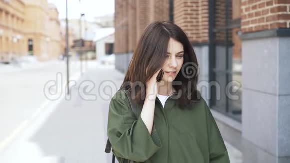 可爱的女孩穿着绿色衬衫在大街上打电话前景视频的预览图