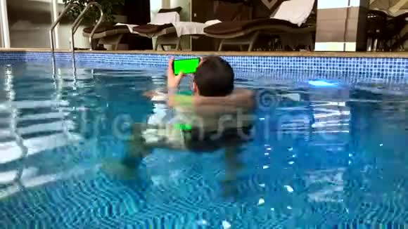 在泳池里使用智能手机的中年男人视频的预览图