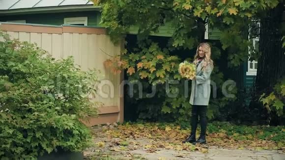 灰色的女孩带着一束黄色的秋叶摆着秋天视频的预览图