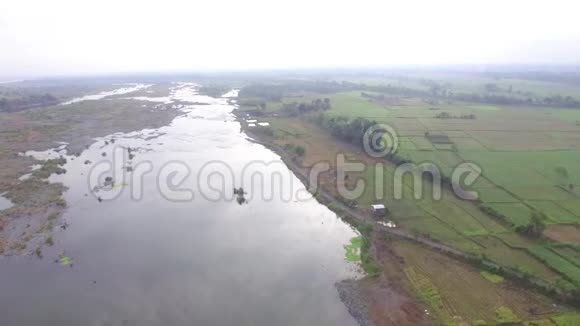 在小农耕社区村里巨大的安静阴暗的浅水河水流淌着低空飞行无人机空中飞行视频的预览图