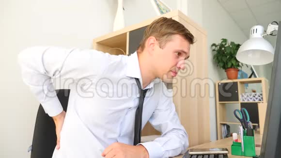 一个年轻人在电脑上工作时背痛4k慢动作视频的预览图