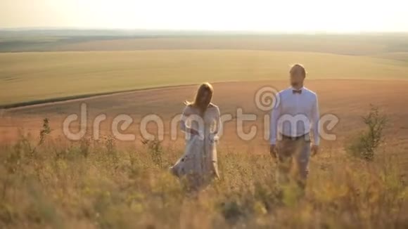 在风景如画的乡村背景下美丽男人和女孩沿着田野走了一天视频的预览图