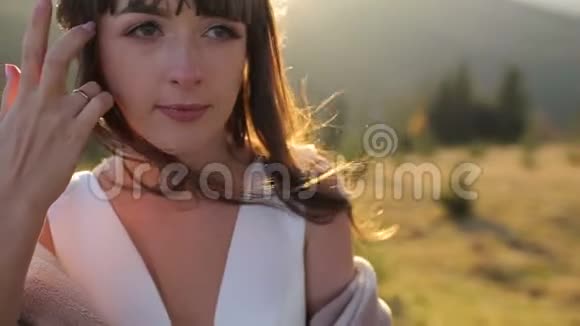 夕阳西下的山坡上有一个年轻美丽的新娘风的天气头发和面纱在颤抖视频的预览图