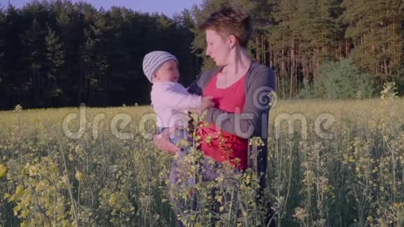 妈妈把宝宝放在油菜田里慢动作视频的预览图