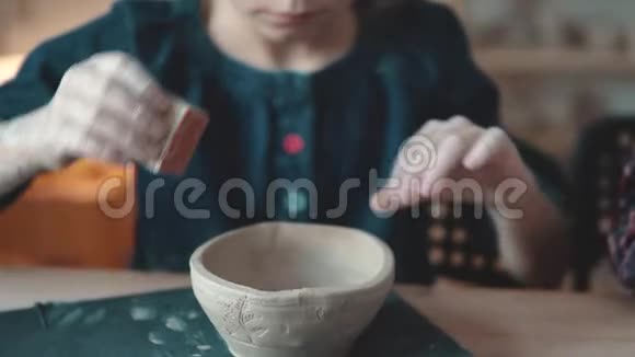 孩子正在做一盘粘土陶艺课小女孩在粘土邮票上做图案视频的预览图
