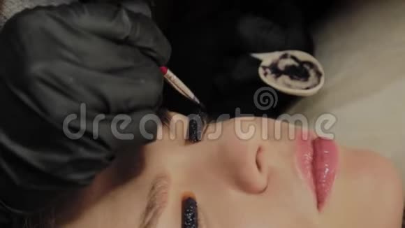 一个非常漂亮的女孩在美容院做一个层叠睫毛美容师把油漆涂在睫毛上视频的预览图