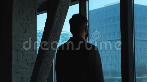 年轻的成功商人在市中心向窗外张望商业大厦阁楼风格的办公室视频的预览图