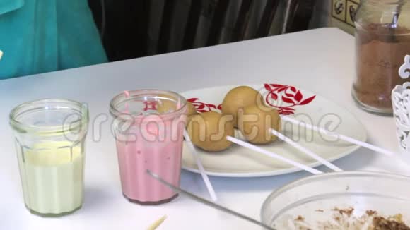 用棍子筷子做流行蛋糕的饼干球躺在盘子里桌子附近有带糖霜的眼镜视频的预览图