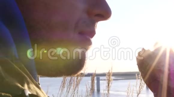 日落时分一个男人在户外咬一个汉堡用太阳的镜头3840x21604K视频的预览图