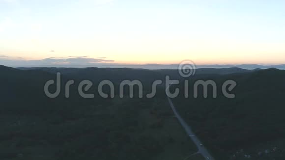 空中无人机在日落时看到青山之间的道路视频的预览图