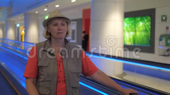 一位女游客正站在机场的一个移动扶梯上视频的预览图