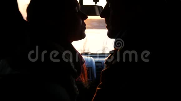 日落时分年轻的男人和女人坐在车里亲吻和微笑慢动作1920x1080全高清视频的预览图