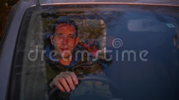 一个年轻人坐在汽车的车轮前挥动着他的手慢动作1920x1080全高清视频的预览图