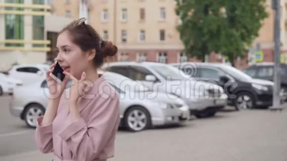 年轻女子在街上用手机说话视频的预览图