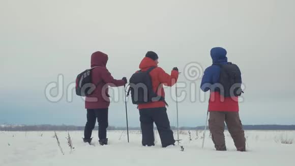 三个徒步旅行者带着徒步旅行杆背包和雪鞋的后景带背包的快乐徒步旅行者小组视频的预览图
