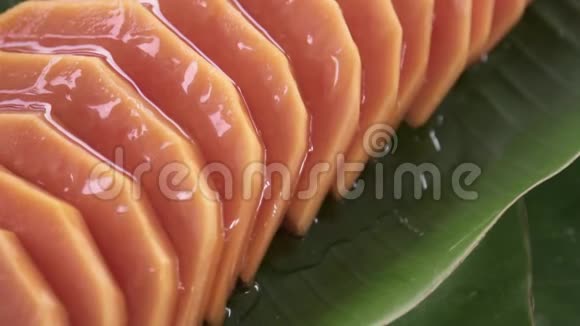 把糖浆倒在香蕉叶上旋转的新鲜泰国热带水果番木瓜片上视频的预览图