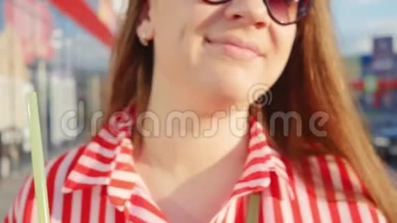 夏天穿红色衣服的年轻女孩的肖像女孩从稻草中喝酒近距离射击视频的预览图