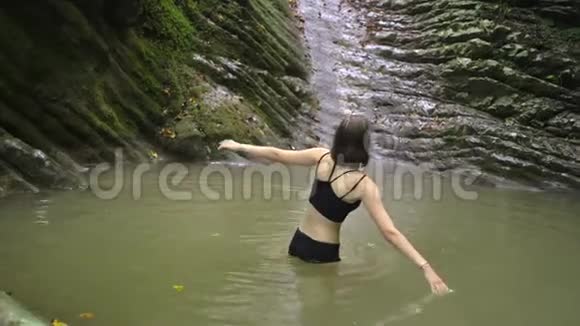 在绿色热带森林的小山湖里洗澡的年轻女子视频的预览图