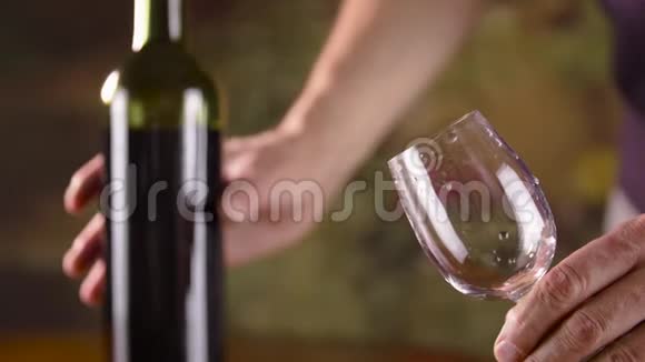 男人用手从瓶子里往杯子里倒红酒喝红酒的人视频的预览图