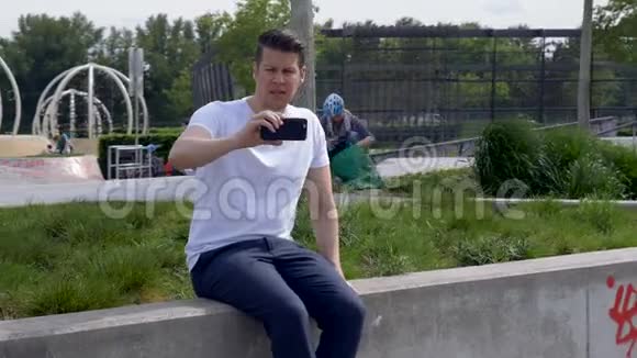 一个坐在公园里用智能手机拍电影的人视频的预览图