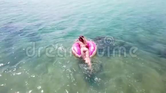 年轻女性在海里用充气环游泳鸟瞰图视频的预览图