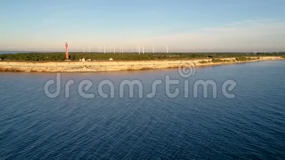 从海洋和陆地上的旧灯塔和风力涡轮机上可以鸟瞰海岸线视频的预览图