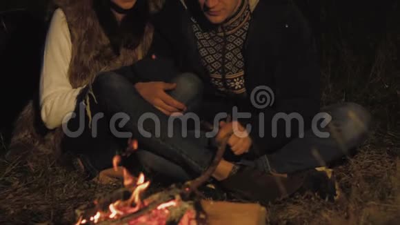 这对可爱的夫妇在森林里的篝火旁休息生火视频的预览图
