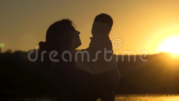 母亲和婴儿在日落时拥抱慢动作视频的预览图