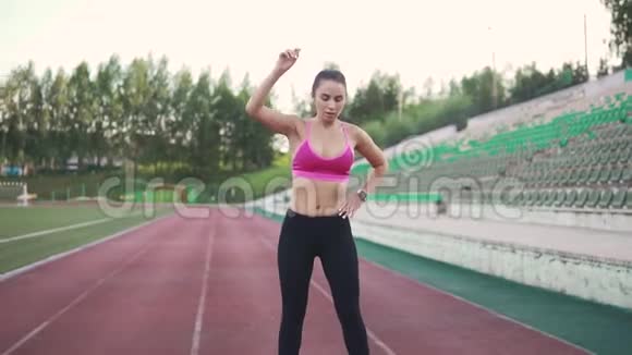 女运动员在训练前热身穿着运动服的女孩在穿过体育场前做伸展运动慢慢慢慢视频的预览图