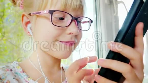 酷的金发女孩使用了6年的手机在她的耳机上她笑积极的情绪在阳光下伤口上的伤口视频的预览图