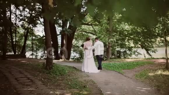婚礼当天幸福夫妇在公园散步最后接吻漂亮的白色婚纱礼服视频的预览图