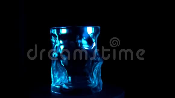 玻璃酒杯在黑色背景的蓝色背光下旋转视频的预览图
