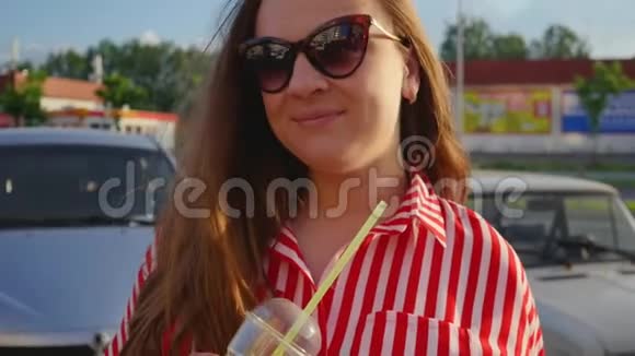 夏天穿红色衣服的快乐年轻女孩的肖像女孩从稻草中喝酒近距离射击视频的预览图