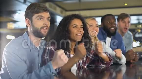 快乐男女在酒吧观看体育比赛庆祝球队胜利视频的预览图
