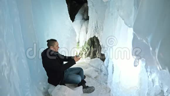 人类在一个冰洞里用智能手机交流围绕着神秘美丽的冰窟用户在社交中交流视频的预览图