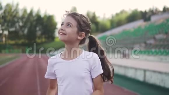 小女孩喜欢慢跑那孩子沿着体育场的跑道跑视频的预览图