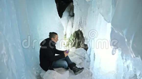人类坐在冰洞里的平板电脑上围绕着神秘美丽的冰窟用户在视频的预览图