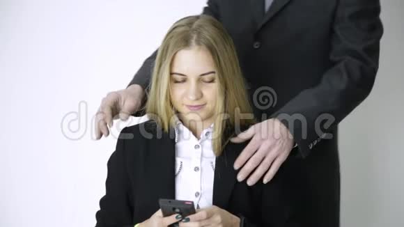 女商人在手机上自拍雇员在做了很长时间的工作后会按摩她的肩膀和脖子视频的预览图