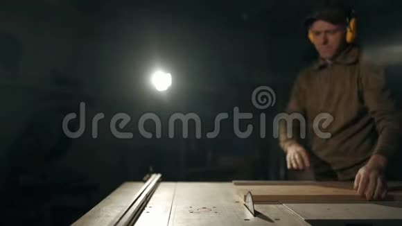 一个专业的木匠正在用一个特殊的电锯来切割一个长方形的木条在办公桌前工作视频的预览图