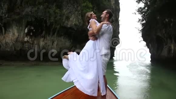 新郎用腰托新娘站在长尾木船上视频的预览图