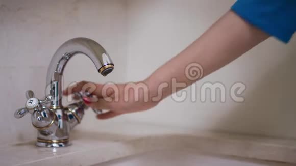 女人手转动旋钮打开浴室的水龙头视频的预览图