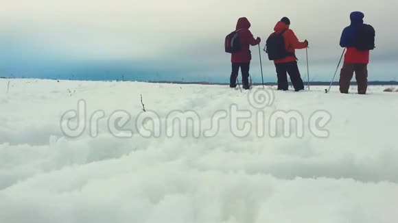 三个徒步旅行者带着徒步旅行杆背包和雪鞋的后景带背包的快乐徒步旅行者小组视频的预览图