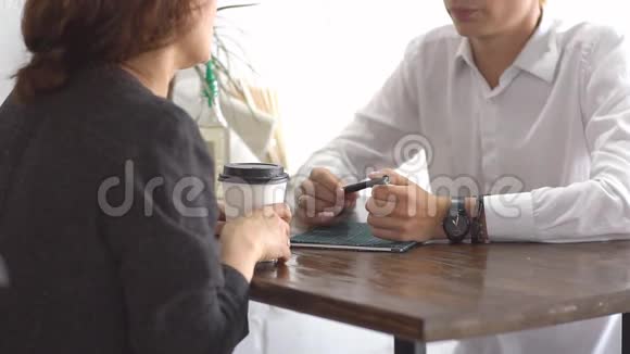 商务伙伴坐在咖啡厅用智能手机在咖啡休息时间聊天视频的预览图