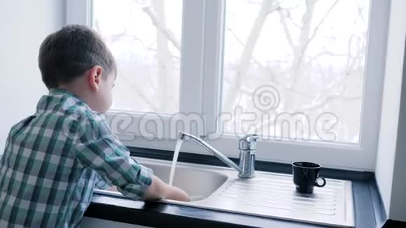儿童洗盘子在水槽到厨房的窗户背景视频的预览图