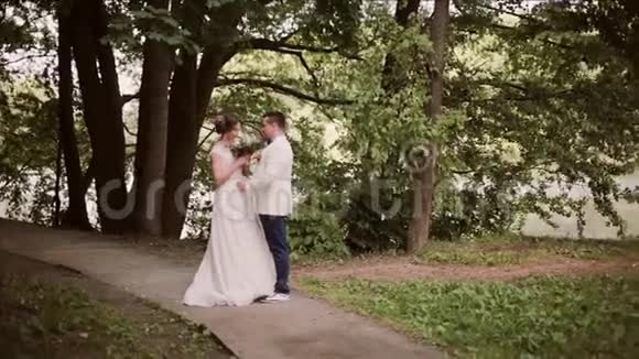 恋爱中的夫妻分享他们的婚礼他们高兴地站在公园里闻着美丽的新娘花束视频的预览图